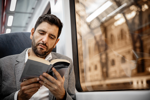 Businessman reading a book in the wagon of a train