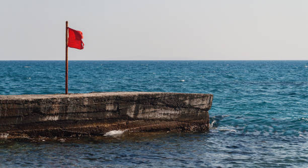 Pier with a red flag in the sea stock photo