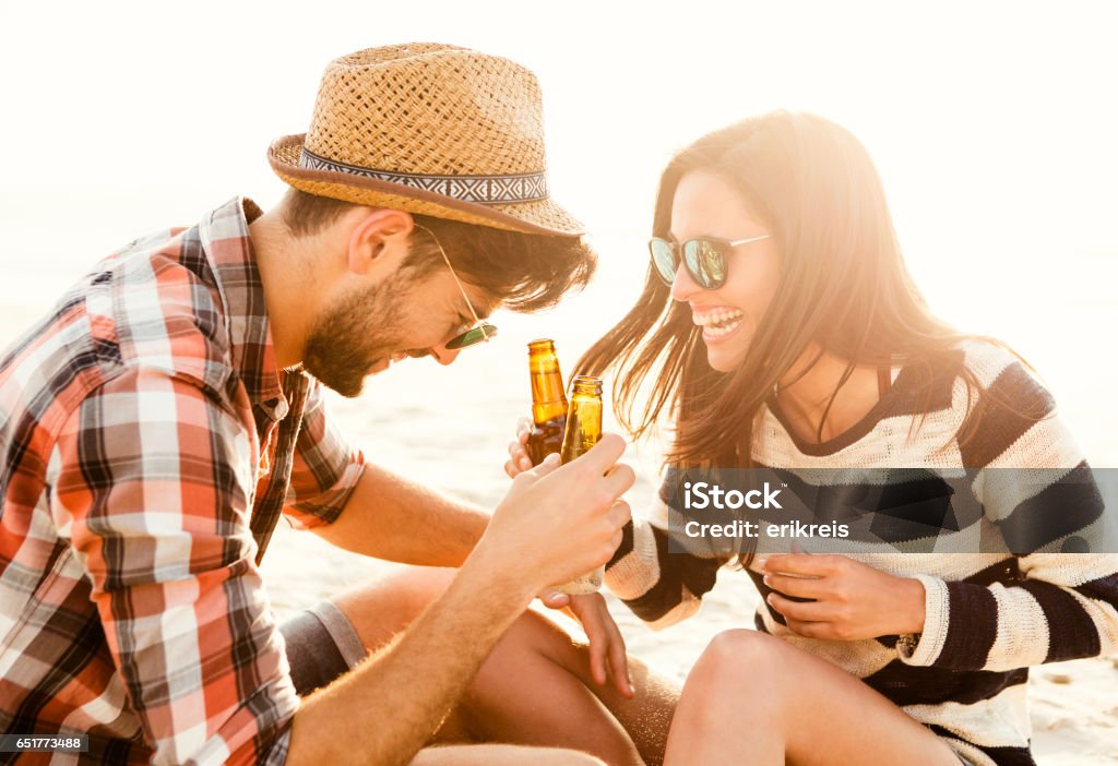 Couple having great time together Young couple at the beach having fun, laughing and drinking beer Beer - Alcohol Stock Photo