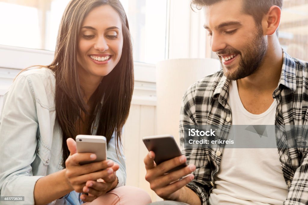 Friends sending a text message Friends at the a coffee shop sending a text message Mobile Phone Stock Photo