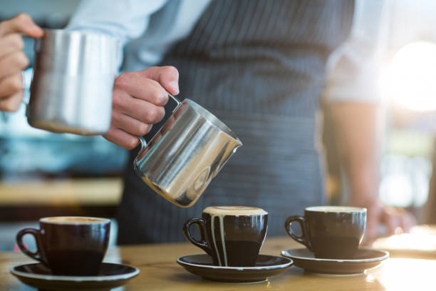 istock Waiter making cup of coffee at counter in cafe 651787488