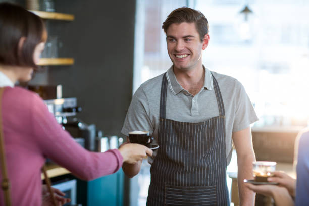 istock Waiter serving a cup of coffee to customer at counter 651788322