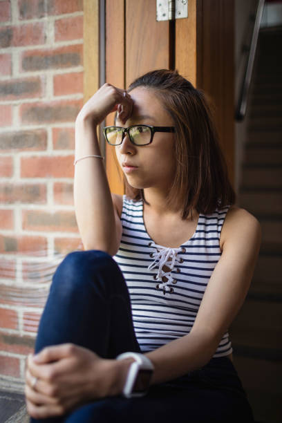 istock Thoughtful woman sitting on windowsill 651788622
