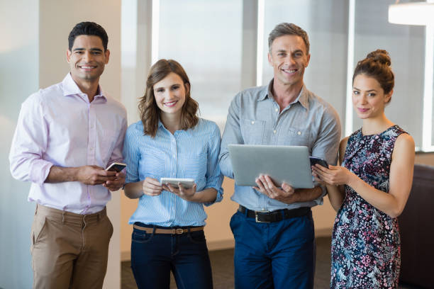 istock Smiling business colleagues using mobile phone, digital tablet and laptop 651791050