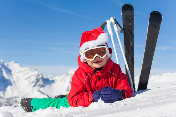 Cute little skier in Santa's hat laying on snow stock photo