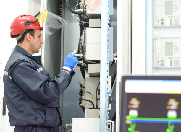 istock Tehnician with red hardhat testing equipment in electrical room 651795362