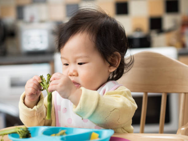 istock baby girl eating vegetable first time 651798048