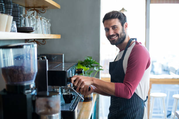 istock Smiling waiter making cup of coffee at counter in cafe 651812006