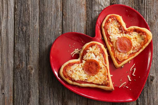 istock Two mini heart pizzas served in heart shaped red plate, top view 651851682