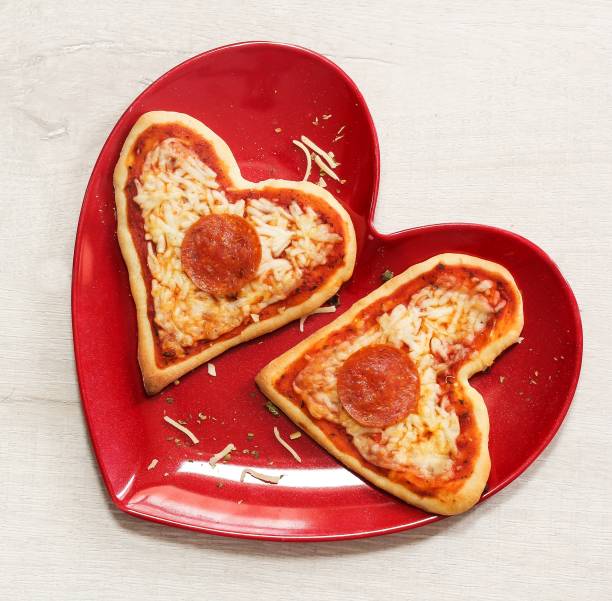 istock Two mini heart pizzas served in heart shaped red plate, top view 651851906