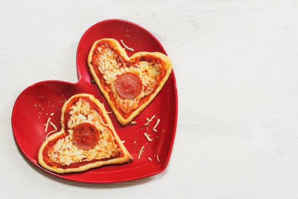 istock Two mini heart pizzas served in heart shaped red plate, top view 651852416