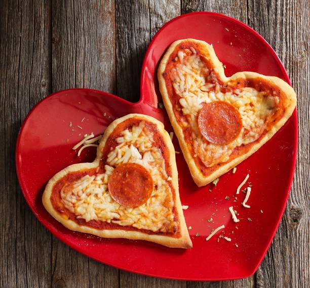 istock Two mini heart pizzas served in heart shaped red plate, top view 651852610