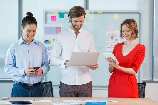 istock Smiling business colleagues using mobile phone, digital tablet and laptop 651853876
