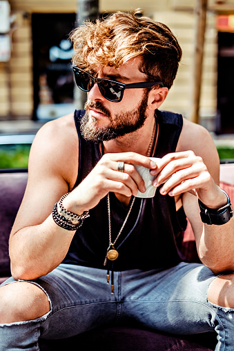 Serious hipster man drinking espresso in cafe on a sunny day