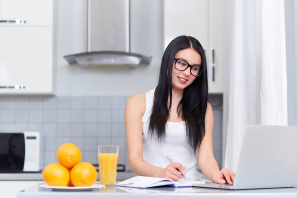 istock Brunette girl planing day at kitchen and using laptop 651891734