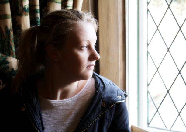 istock young woman looking out of window 651912678