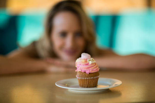 istock Woman looking at cupcake on plate 651916186