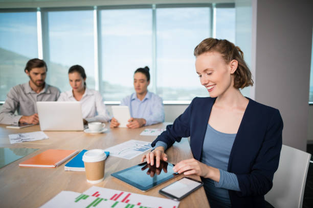istock Smiling female business executive using digital tablet in conference room 651970198