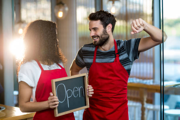istock Waitress and waiter standing with open sign board in cafe 651970678