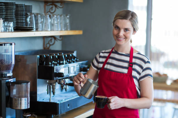 istock Smiling waitress making cup of coffee at counter in cafe 651970692