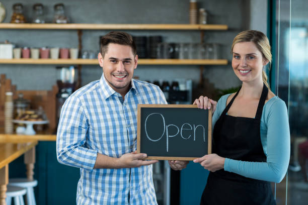 istock Waitress and man standing with open sign on slate in cafe 651970970