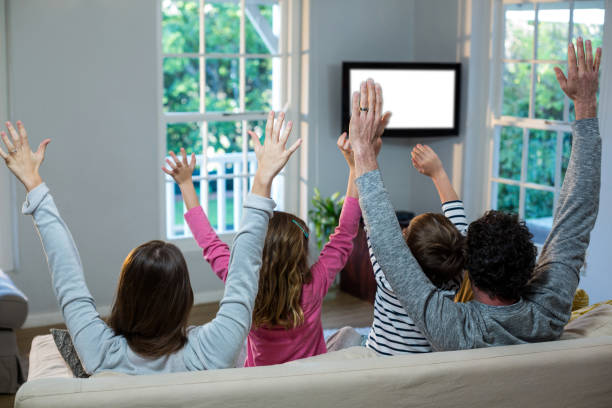 istock Family raising hands while watching television 652137166