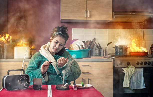 Young girl talking phone Careless girl talking on phone and makinger her nails while the kitchen is on fire. careless stock pictures, royalty-free photos & images