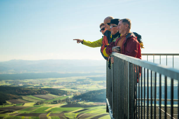 four senior hikers on viewpoint in the austrian mountains looking into the distance