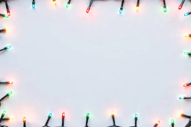 Photo of colorful glowing garland on white background Christmas frame mockup