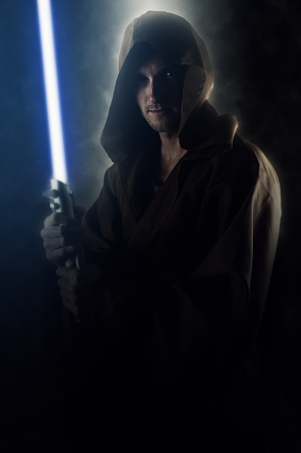 Young warrior holding a lightsaber over a dark background