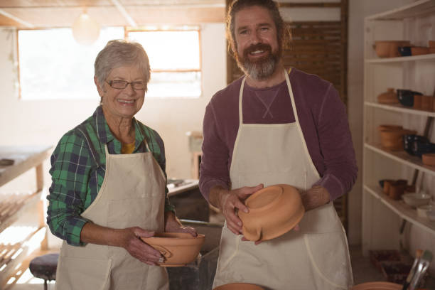 istock Male and female potter holding pots 652180466