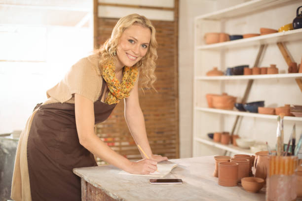 istock Portrait of female potter writing in notebook 652188688
