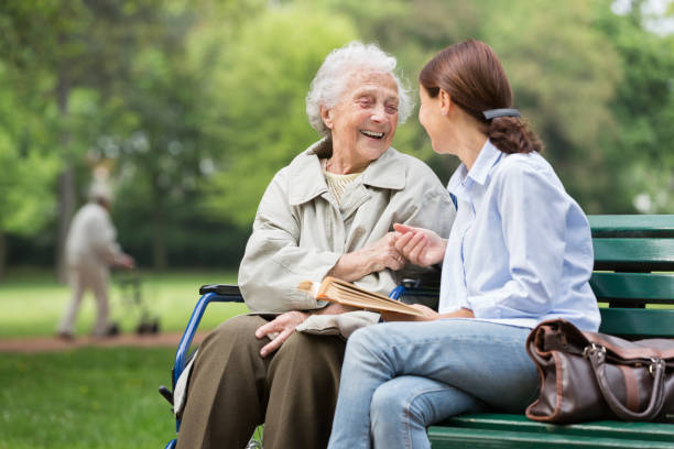 Senior woman with caregiver in the park stock photo