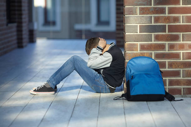 школьник плачет в коридоре школы - school стоковые фото и изображения