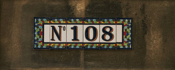 istock House number one hundred and eight sign on stone wall 652199910