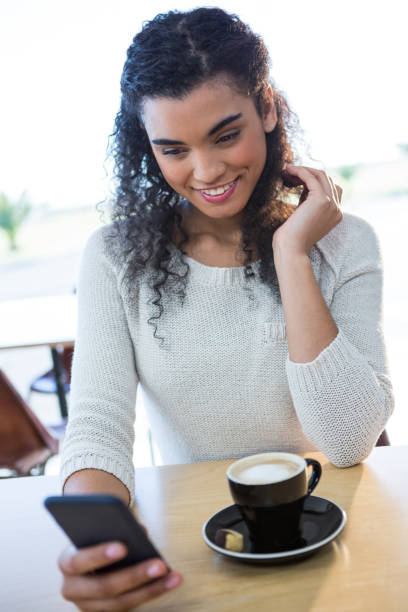 istock Woman using mobile phone and a coffee cup on the table in coffee shop 652203362