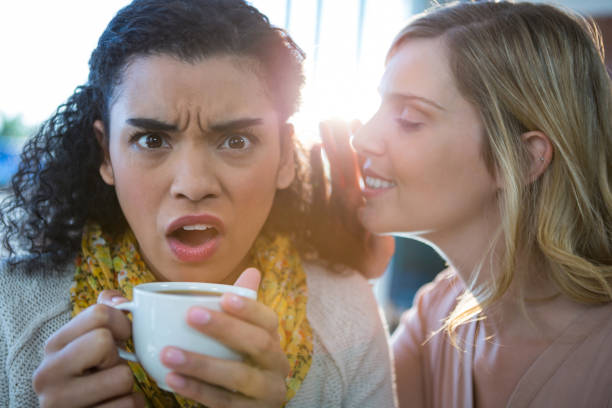 istock Woman whispering a secret into her friends ear while having coffee 652203452