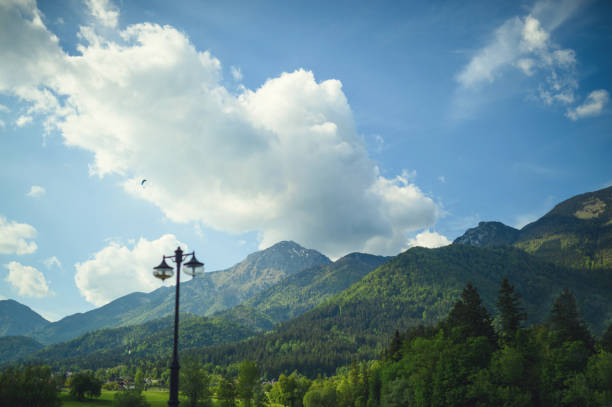 Walchensee, Germany - August 23, 2017: Silhouettes of two woman with backpacks against sky and alpine mountain tops. Side view