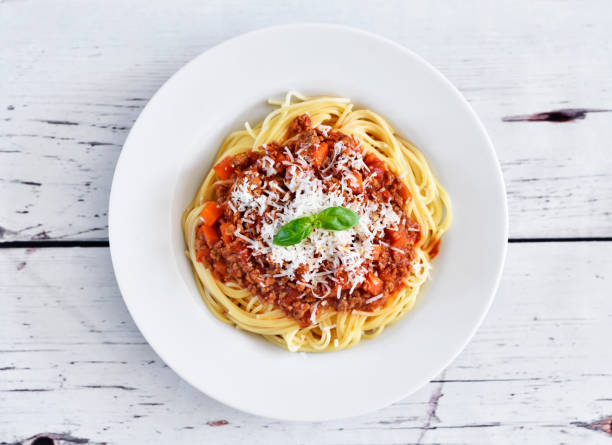 Spaghetti Bolognese on a white plate Spaghetti Bolognese on a white plate with decorative basil leaf. Italian cuisine, pasta with tomato sauce and parmesan cheese. sauce photos stock pictures, royalty-free photos & images