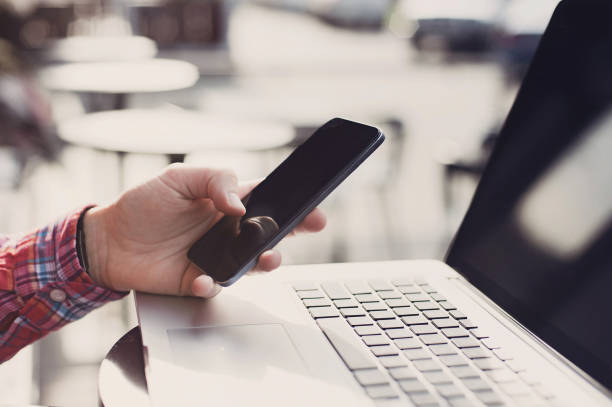 istock Young man using smart phone and laptop outdoors 652225104