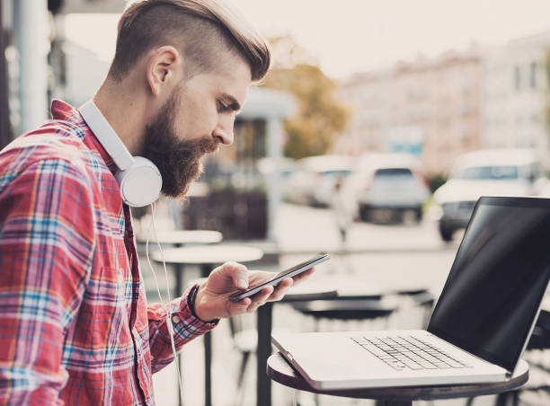 istock Young man using smart phone and laptop outdoors 652225106