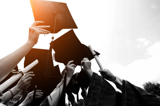 Group of graduate students throwing graduation hats to the sky.