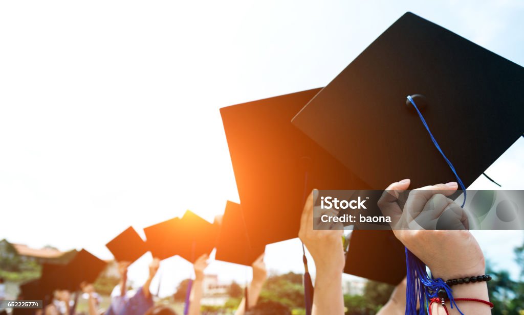 holding graduation hats Group of graduate students holding their graduation hats. Graduation Stock Photo