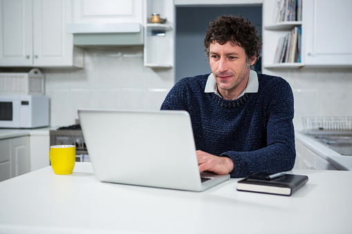 Man using laptop in the kitchen at home