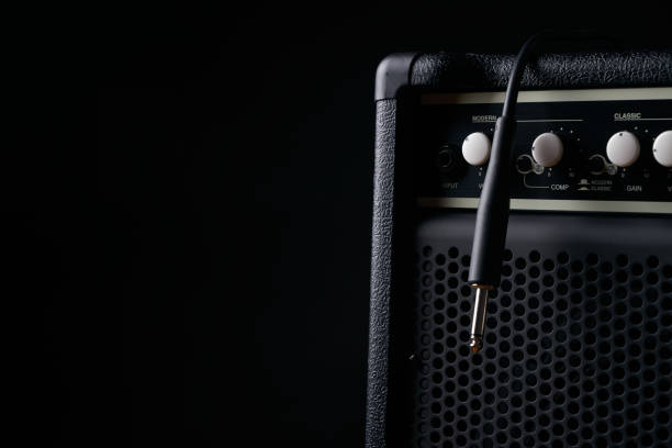 Close up of Black guitar amplifier with jack cable on black background.