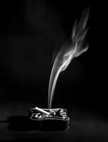 Ashtray and cigarette smoke, black and white detail