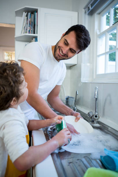 istock Son helping father in washing utensils 652235986