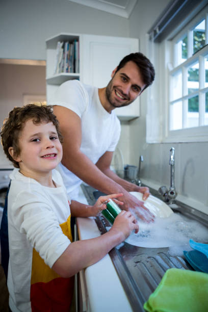 istock Son helping father in washing utensils 652236020