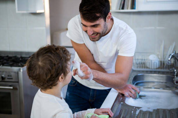 istock Son helping father in washing utensils 652236022
