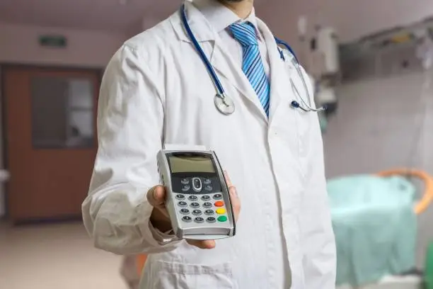 Photo of Doctor is holding payment terminal in hands